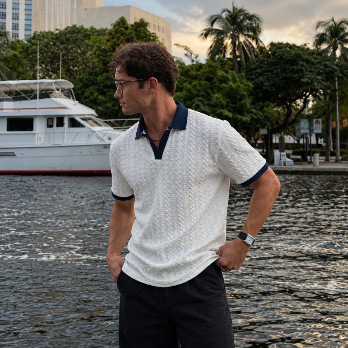 Modelo com camisa polo masculina branca de textura trançada e gola azul-marinho, vista de lado