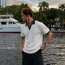 Modelo com camisa polo masculina branca de textura trançada e gola azul-marinho, vista de lado
